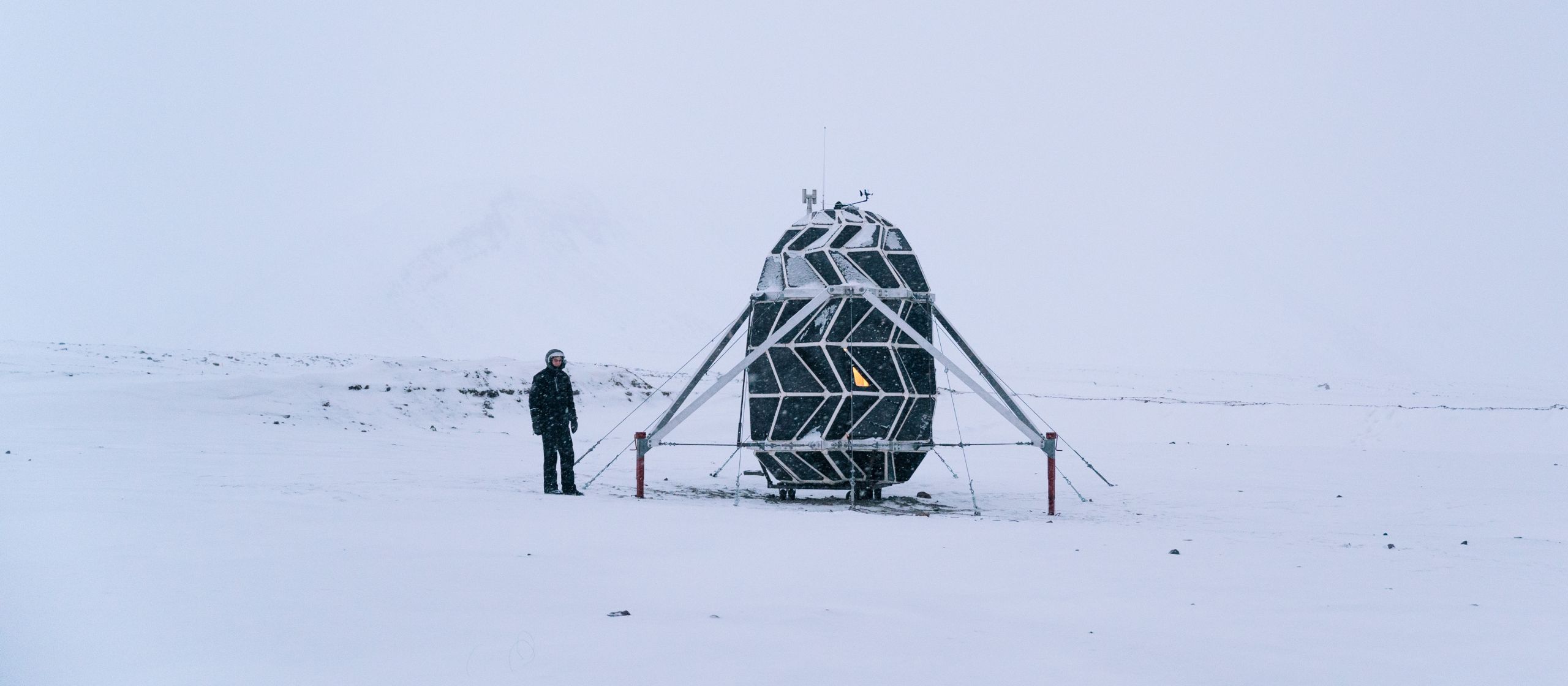 Image of the Lunark habitat in snow with a crew member standing next to it